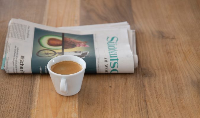 fotografia di giornale e tazzina di caffè su tavolo di legno.