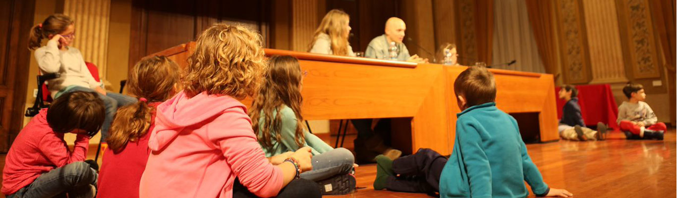 Photo of a Reading in the dark event. The author is surrounded by a group of kids