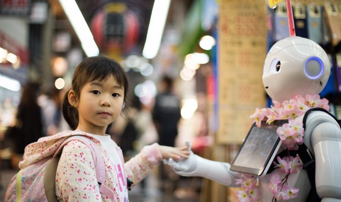 Fotografia di un robot con sembianze umane che porge la mano a una bambina