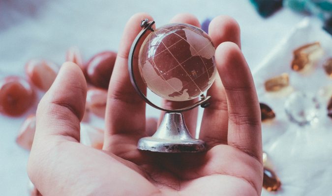 Fotografia di una mano che regge un globo in miniatura