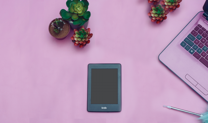 photograph of a kindle on a table with succulents and a laptop