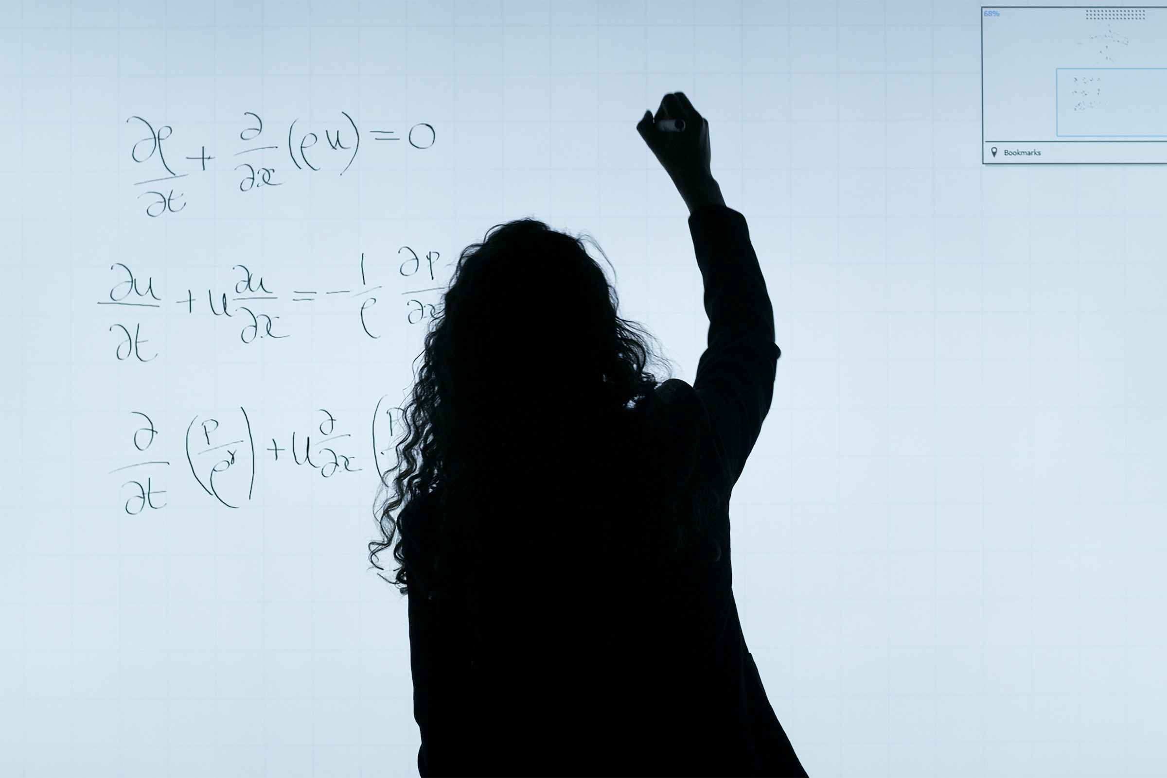 photograph of a woman writing mathematical formulas on a blackboard