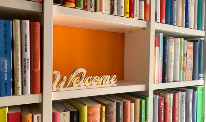 Fotografia di uno scaffale con dei libri e la scritta Welcome